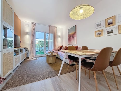 Área de estar moderna de la Casa Rural Estartit con comedor, sofá, televisión y vistas al jardín
