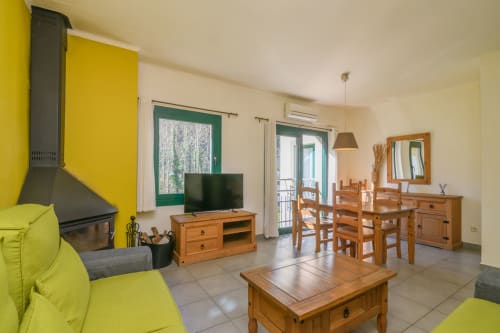 Spacious 2-bedroom apartment at Rural Montseny with lime-green seating, wooden furniture, TV, fireplace, and mountain views