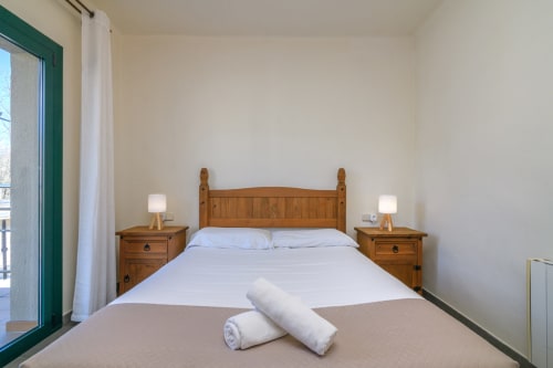 Bright bedroom at Rural Montseny apartment in Gualba with wooden bed, white linens, and side tables with lamps