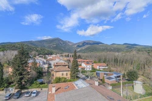 Aerial view of Rural Montseny apartment in Gualba with mountains, valley forest, and village buildings