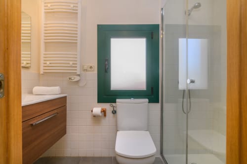 Modern bathroom in Rural Montseny apartment with toilet, sink, shower enclosure, and wood vanity
