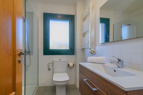 Modern bathroom in Rural Montseny apartment with sink, toilet, window, mirror and heated towel rack