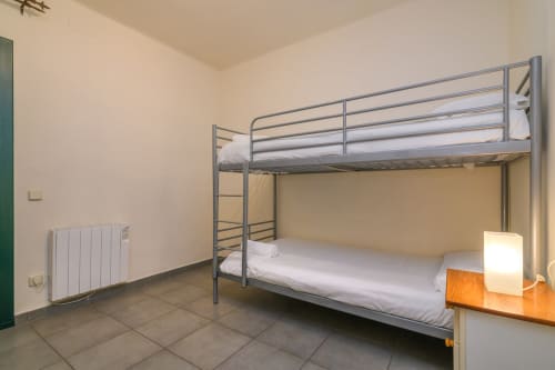 Modern bunk bed room at Rural Montseny apartment in Gualba with metal frame beds, white bedding, radiator, and tiled flooring