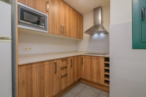 Modern kitchen with wooden cabinets, white countertops, stainless steel appliances and range hood in Rural Montseny apartment