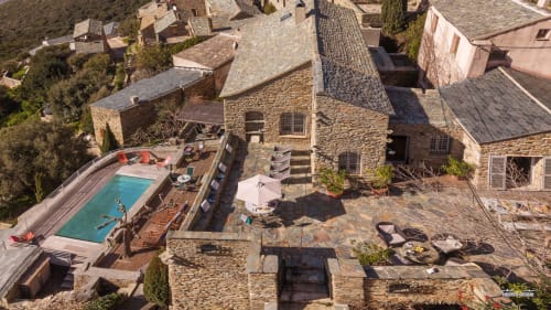 Vue aérienne de la Villa Cecile à Centuri, Corse avec piscine, bâtiments en pierre et terrasse aménagée