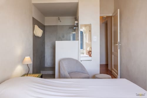 Chambre moderne de la Villa CECILE à Centuri, avec salle de bain attenante, douche carrelage gris, fauteuil et design minimaliste
