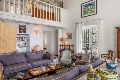 Spacieux salon de villa à Centuri, Corse avec canapés violets, mobilier en bois et mezzanine à La Conciergerie du