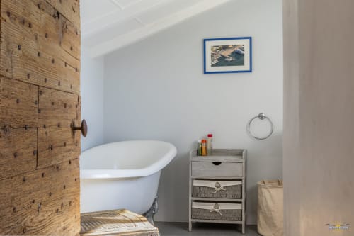 Salle de bains moderne de la Villa CECILE avec baignoire îlot, porte en bois, meuble de rangement et vue sur la mer à La Conciergerie