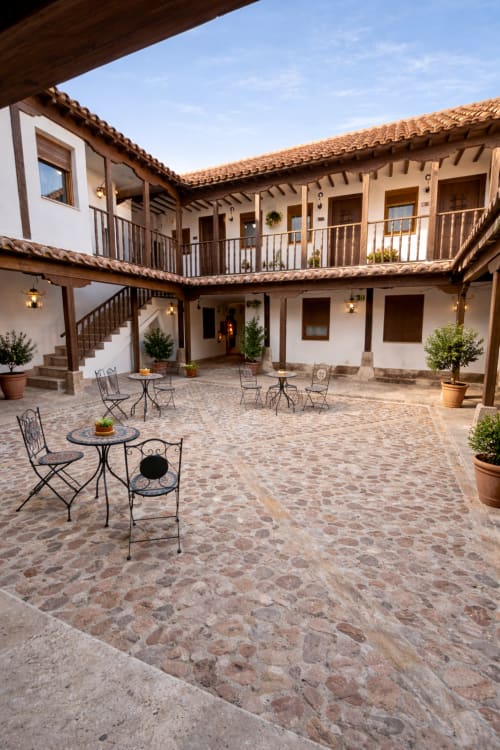 Colonial courtyard at Retiro del Teatro, Almagro with whitewashed walls, terracotta tiles, and wrought iron seating