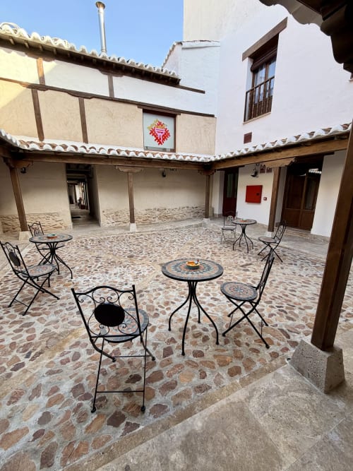 Historic courtyard at Retiro del Teatro in Almagro with wrought iron seating, decorative tile tables, and traditional Spanish