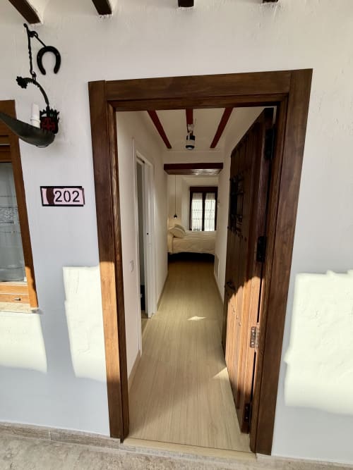 Room 202 hallway entrance at Complejo Turístico Retiro del Teatro in Almagro with wooden beams and leading to bedroom