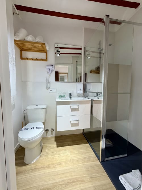 Modern bathroom at Retiro del Teatro, Almagro with walk-in shower, double sink and wood flooring