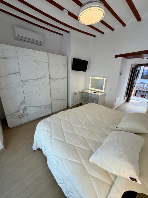 Modern bedroom at Complejo Turístico Retiro del Teatro with queen bed, marble wardrobe, vanity mirror, and wooden beamed