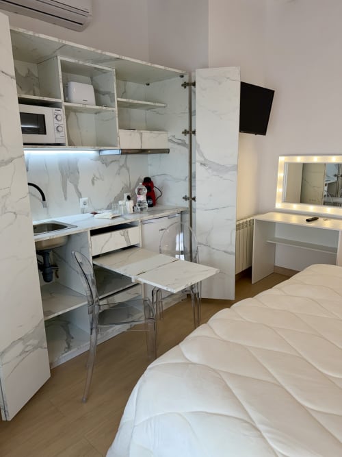 Modern studio room at Retiro del Teatro, Almagro with marble kitchenette, bed, dining table and vanity mirror