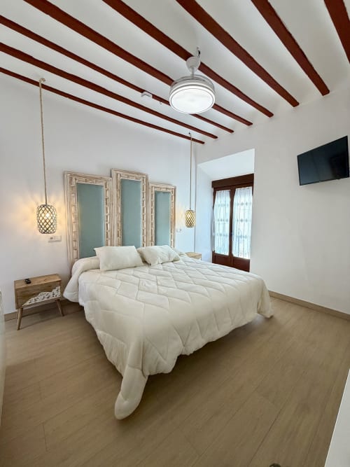 Modern bedroom at Complejo Turístico Retiro del Teatro with beamed ceiling, cream bedding, and wooden flooring in Almagro