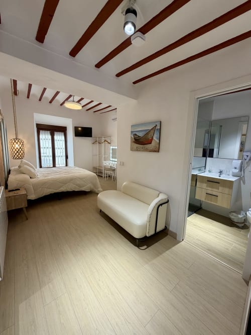 Modern bedroom at Complejo Turístico Retiro del Teatro, Almagro with beamed ceiling, queen bed, seating, and ensuite bathroom
