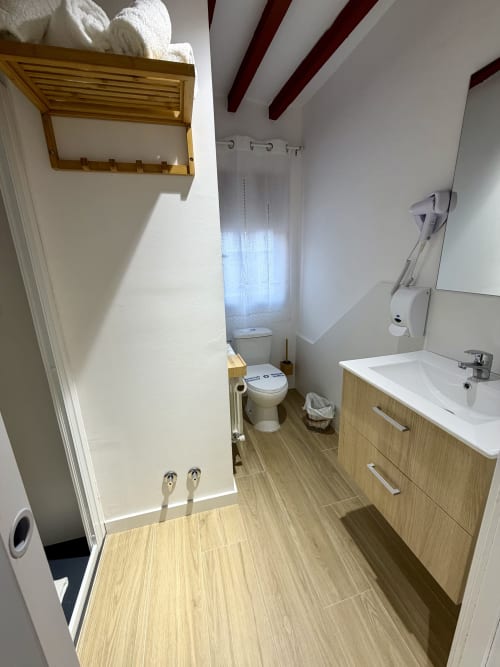 Modern bathroom at Retiro del Teatro with wooden vanity, shower, toilet, and natural light in Almagro