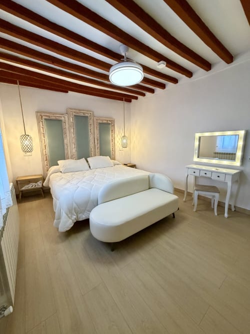 Modern bedroom at Retiro del Teatro with exposed beams, white bedding, vanity mirror, and contemporary furnishings in Almagro