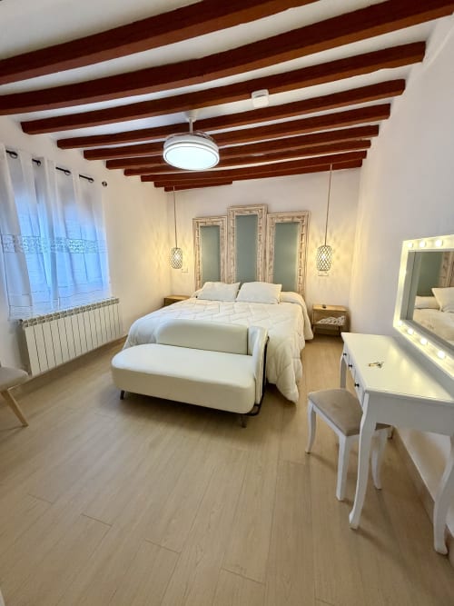 Modern bedroom at Complejo Turístico Retiro del Teatro with exposed wooden beams, white linens, and contemporary furnishings
