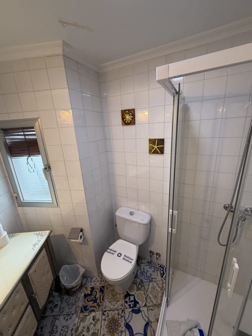 Baño moderno en la casa rural Villa Corral de Comedias del Complejo Turístico Retiro del Teatro, con azulejos blancos y inodoro