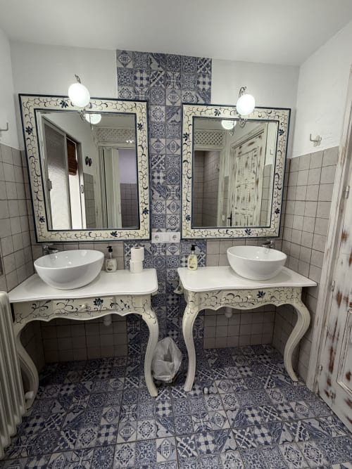 Elegante baño con dos lavabos en Villa Corral de Comedias, azulejos azules y blancos, espejos ornamentales y lavabos tipo recipiente.