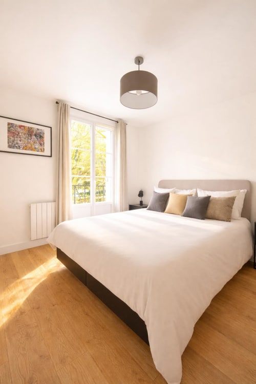 Chambre moderne et lumineuse à la Résidence Disneyland Place Toscane avec lit queen-size, lampe suspendue et vue sur le jardin