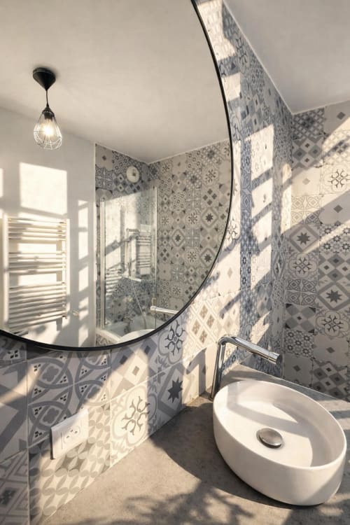 Salle de bain moderne à la Résidence Disneyland Place Toscane avec carrelage à motifs, miroir arrondi, lavabo blanc et zone douche