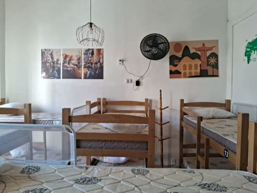Quarto compartilhado no Rio Vibes Hostel com camas beliche de madeira, paredes brancas e decoração temática do Rio de Janeiro