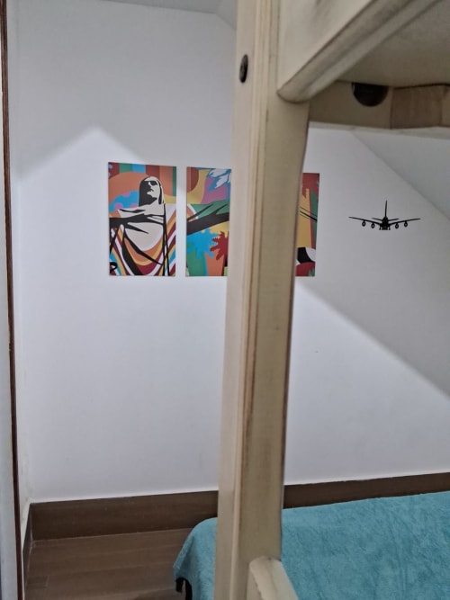 Quarto triplo Rio Vibes Hostel com adesivos pop art coloridos e design de silhuetas de aviões em paredes brancas