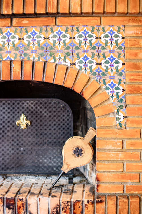 Fireplace detail at Finca Navalpino with decorative Iberian tiles, terracotta brick arch, and fleur-de-lis ornament in