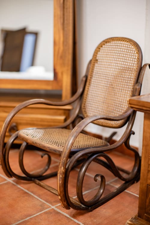 Wooden rocking chair with woven cane seat at Finca Navalpino boutique bed and breakfast in Guadamur, Spain