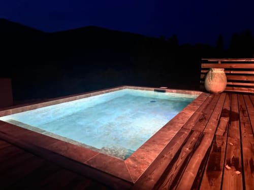 Piscine illuminée à In Casa Conciergerie à Figari surplombant le paysage montagneux au crépuscule