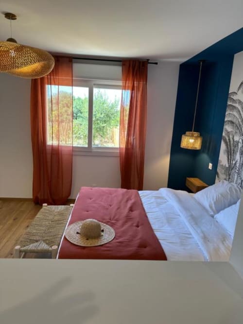 Chambre moderne à l'In Casa Conciergerie de Figari avec vue sur l'océan, suspensions tissées, mur d'accent bleu marine et décor contemporain