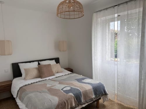 Chambre moderne à In Casa Conciergerie à Figari avec lit noir, décor épuré, suspension tissée et portes vitrées