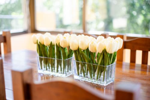 White tulips in glass vases on wooden dining table at Finca Navalpino, Guadamur