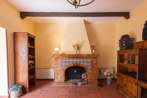 Rustic fireplace with blue-tiled arch in Finca Navalpino's sunny guest room, Guadamur