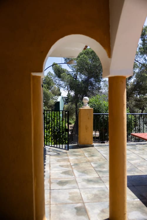 Arched terrace passage at Finca Navalpino with ochre columns overlooking Mediterranean garden in Guadamur