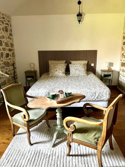 Chambre élégamment aménagée avec chaises d'époque en bois, literie à motifs et murs en pierre au Manoir de Fornebello, Bretagne