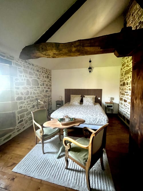 Chambre Kernandu avec poutres apparentes, murs en pierre, vue sur le jardin au Manoir de Fornebello