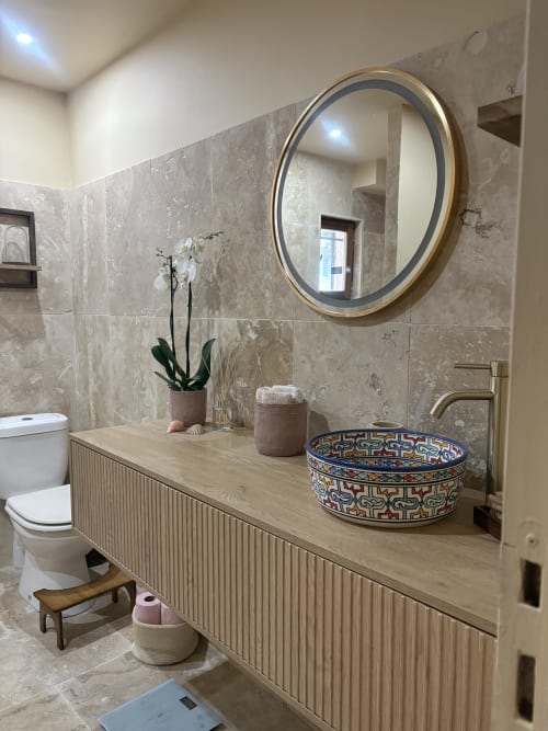 Salle de bains moderne avec miroir rond, vasque décorative et orchidée en pot à l'appartement Conciergerie Maurin à Arles