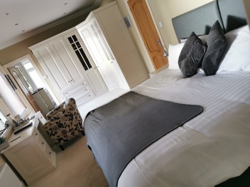 Spacious double bedroom at Arrochoile B&B Glasgow with white wardrobe, desk, and comfortable bed with pillows