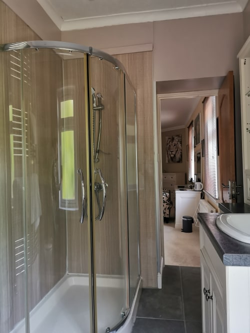 Modern bathroom at Arrochoile Glasgow B&B with curved glass shower enclosure and pedestal sink