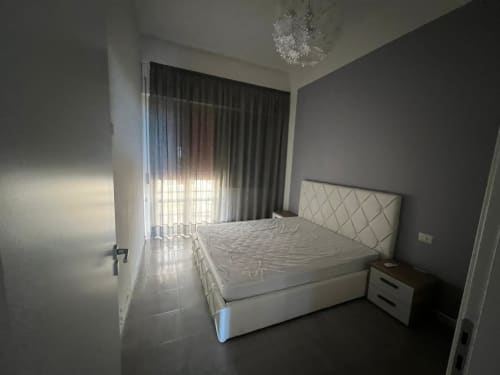 Camera da letto luminosa con letto queen size, parete grigia in evidenza e tende che affacciano sul mare nell'appartamento fronte spiaggia di Marina di Strongoli