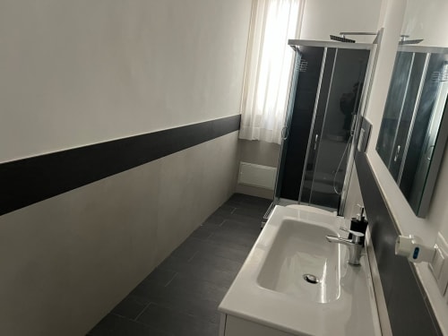 Bagno moderno con piastrelle bianche e nere, lavabo bianco, rubinetto cromato e doccia in vetro a Marina di Strongoli