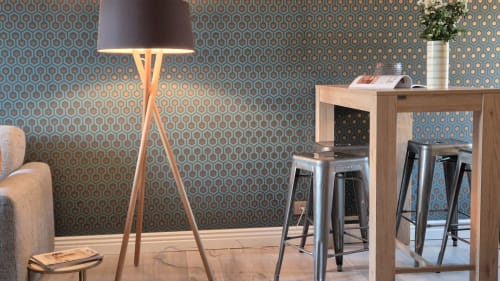 Modern zitgedeelte in het Moulin Renaudiots met geometrisch behang, houten bureau, barplaatsen en vloerlamp