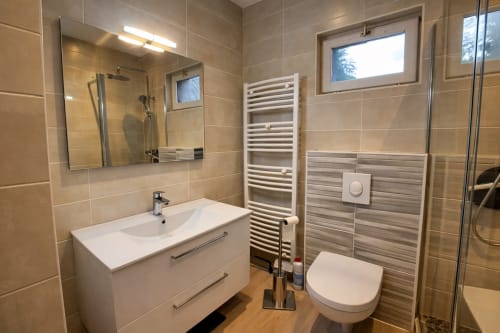 Salle de bain moderne avec lavabo, miroir et douche à l’italienne au gîte Le Clos Bussy à Vichy