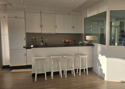 Cucina moderna con mobili bianchi, piano nero e quattro sgabelli bianchi nell'appartamento La Dolce Vita a Campagnano di
