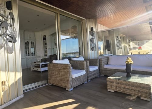 Terrazza vista mare dell'appartamento La Dolce Vita con sedute in vimini, panorama oceanico e accesso agli interni moderni