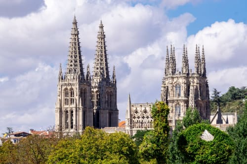 Torres de la catedral gótica de Burgos, España con follaje verde y cielo azul