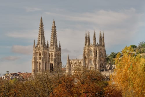 Catedral de Burgos con agujas doradas rodeada de árboles otoñales, monumento icónico cerca del hotel Unique Rooms